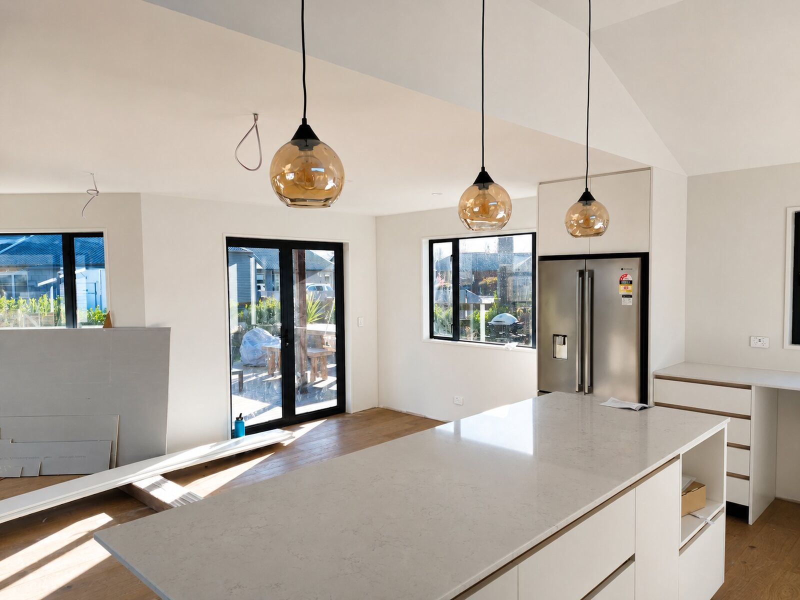 Open plan kitchen under pendant lights, freshly painted