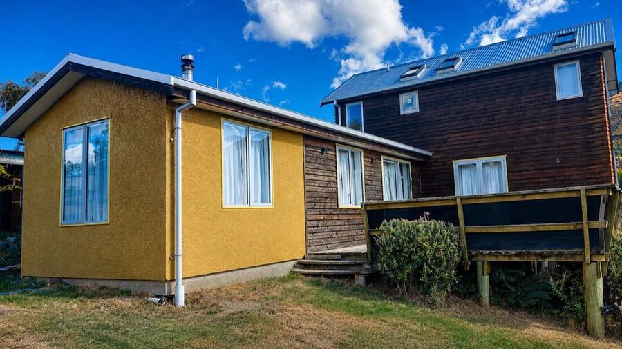 Mustard coloured exterior alongside dark stained cladding before recoating